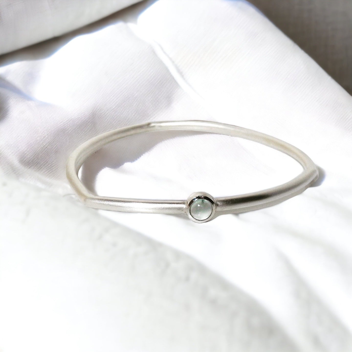 3.2mm soft triangle bangle with 6mm round aquamarine cab bezelled, high polish bezel with matte finish bangle.