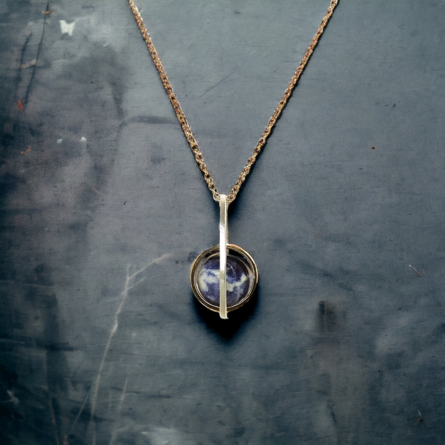 Worldly perspective: new pendant added to the Astral collection . 14 kt yellow gold band within sterling silver wire drop shape holding a free floating worldly looking sodalite undrilled sphere bead.   on 14kty 18" cable chain, by ZEALmetal, Nicole Horlor, in Kingston, ON, Canada