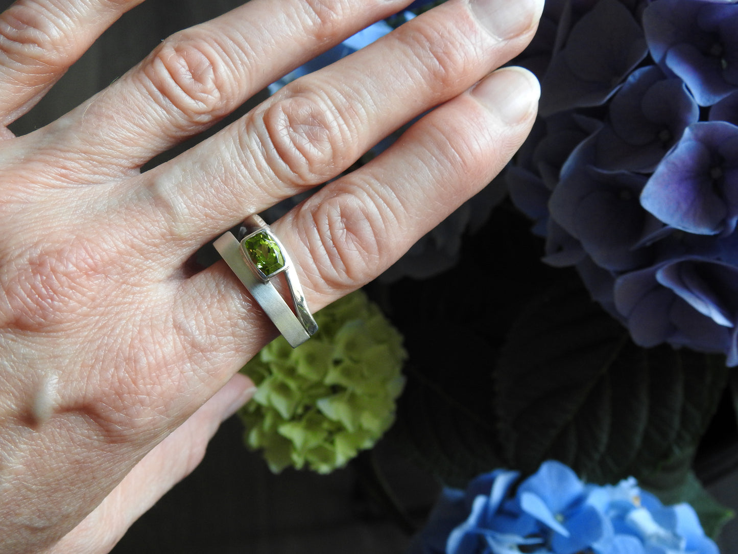 Sterling silver triangle ring, double band with flow and negative space for a bold light look and feel, with a bezel set rectangle facetted peridot, by ZEALmetal, Nicole Horlor, in Kingston, ON, Canada