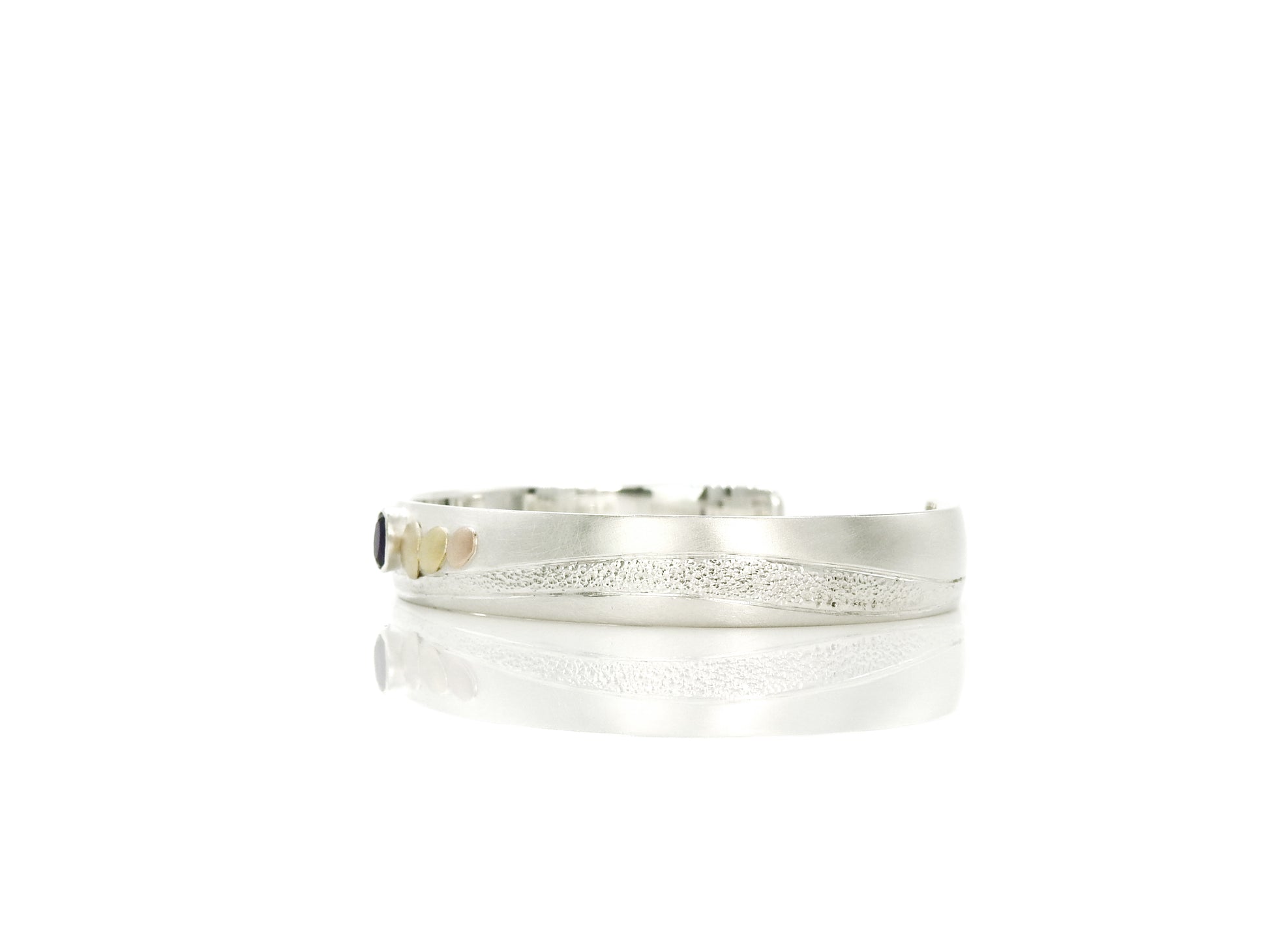 sterling silver with 14kt yellow and red gold pebbles and 18kt yellow gold pebble, with 6x4mm oval facetted amethyst set in sterling silver bezel, hand carving and planish detailing.  bracelet by ZEALmetal, Nicole Horlor, in Kingston, ON Canada