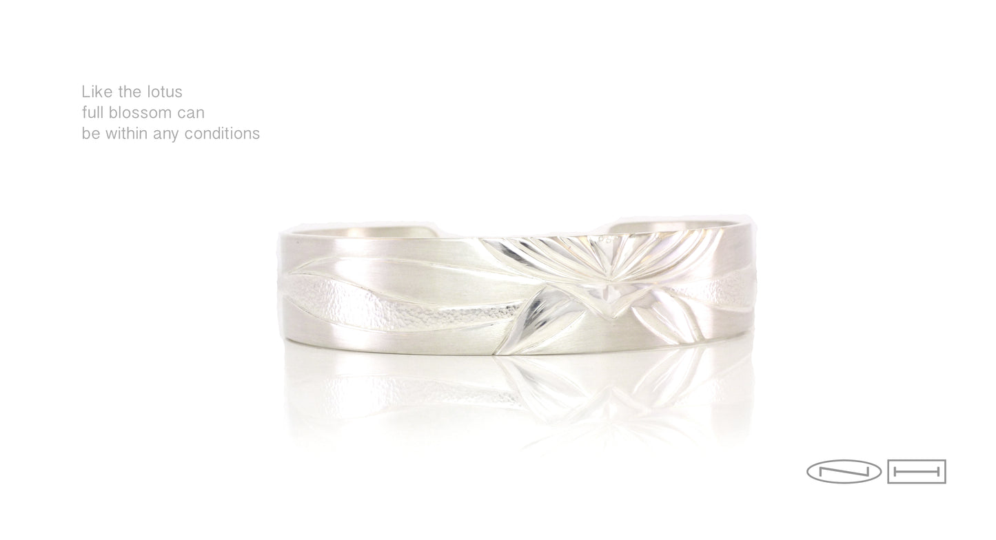 Lotus ~ hand carved bracelet with a single lotus blossom with carved waves showing highs, and lows around the cuff style. Mixed textures of high polish, matte and planishing are used to accentuate the design. Available in white gold, palladium white gold, yellow gold, red gold, marriage of metal ( a combination of more than one colour of gold) and platinum. Please contact for a quote in your size and the desired width. 613-888-6309 N i c o l e H o r l o r